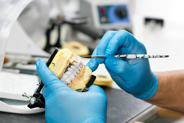 Dentista ajustando prótesis dental sobre modelo de dientes en clínica dental de Dos Hermanas